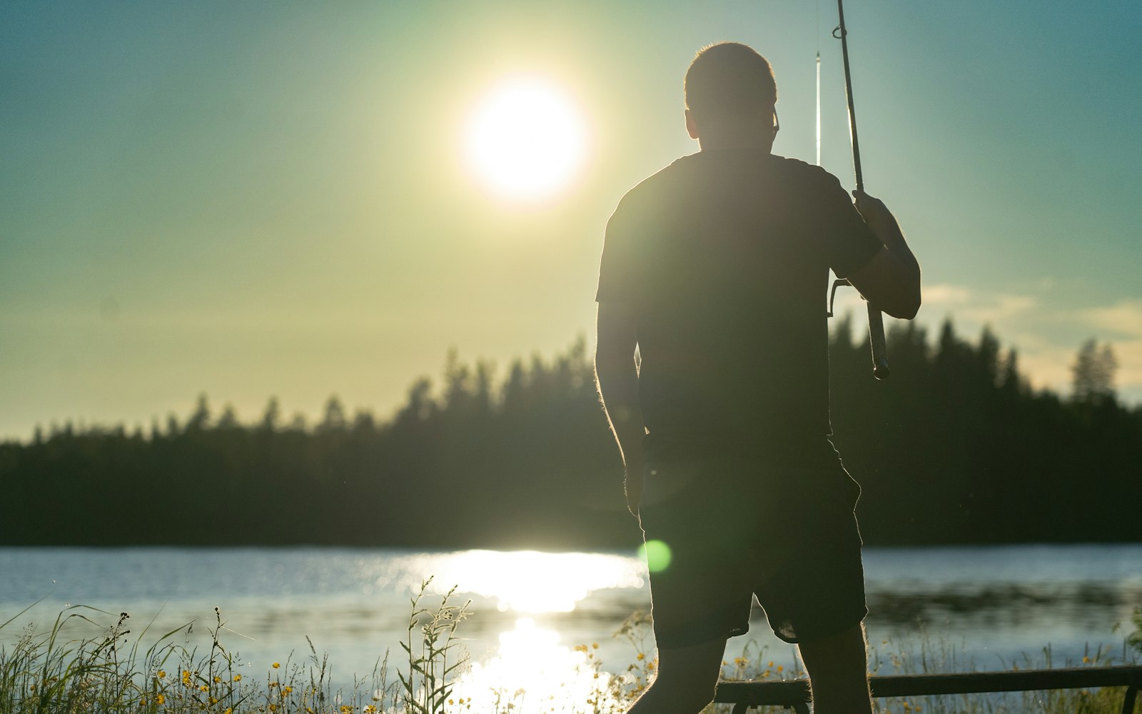 Angler fishing on a calm lake at sunrise